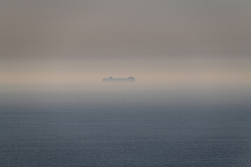 A large ship in the sea mist off the coast of Cornwall in late Spring