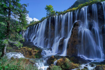 Fototapeta na wymiar Beautiful and fresh scenery at waterfalls with massive cascade, green algae, reflection and trees.