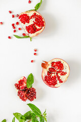 Red pomegranate on a white background. Grenades are scattered on the table. Pomegranate berries glisten on a white background.