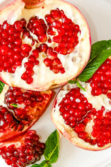 Red pomegranate on a white background. Grenades are scattered on the table. Pomegranate berries glisten on a white background.