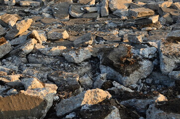 Broken pieces of asphalt at a construction site. Recycling and reuse crushed concrete rubble, asphalt, building material, blocks. Crushed сoncrete Background. Road repair, replacement of old pavement