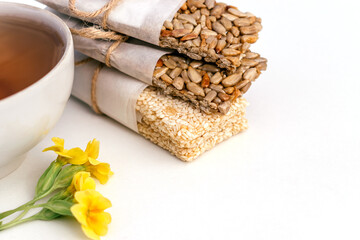Cup of tea and homemade kozinaki from sunflower seeds, sesame on Jerusalem artichoke syrup on a white background.Сoncept of healthy food and healthy desserts.Top view,copy space