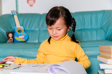 School Home work concept,Asian children wearing yellow casual clothing doing school home work drawing in Living room during the COVID-19 quarantine. Coronavirus isolation. online studying from home