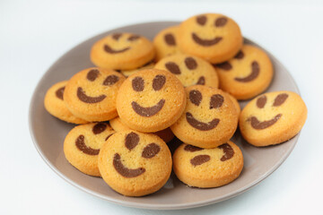 A set of smiling biscuit cookies served on brown plate isolated on white background with copy space. Smile concept. Sweet greeting