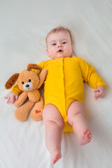 Portrait of infant in bed with a toy in his hand. Vertical photo