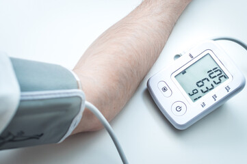 man measures his blood pressure with an automatic blood pressure monitor. Hand and tonometer...