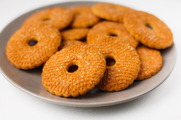 A pile of round biscuits with sugar icing  served on a brown plate isolated on white background top  side view