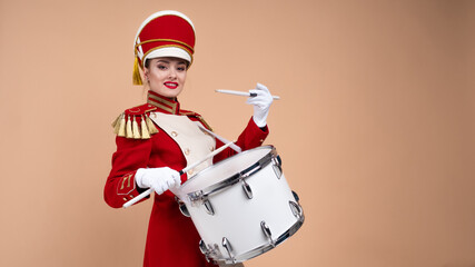 Charming cheerful drummer in a red uniform, sings and plays the drum.