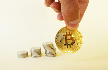 Bitcoin coin in hand and three piles of coins. Bitcoin exchange rate growth or cryptocurrency accumulation.
