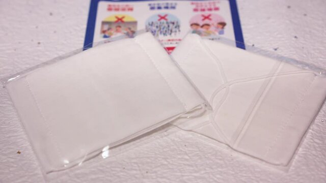 Close-up slide zoom-in video of two cloth masks and a leaflet promoting social distancing sent by Japanese govt of Abe Shinzo Prime minister to fight coronavirus (COVID-19)