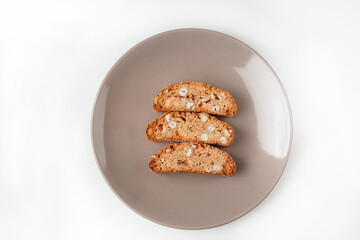 Popular Italian Biscotti or Cantucci biscuit cookies stuffed with nuts on brown plate with copy space.