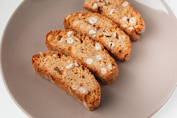 Popular Italian Biscotti or Cantucci biscuit cookies stuffed with nuts on brown plate with copy space.