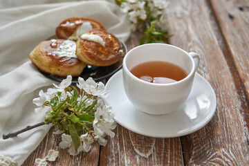 Pile of small homemade pancakes with honey, tea cup and honeycomb on wooden table