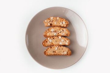 Popular Italian Biscotti or Cantucci biscuit cookies stuffed with nuts on brown plate with copy space.