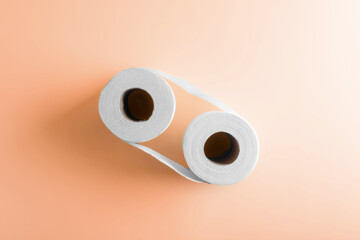 Two roll of toilet paper on peach color paper background. Hygiene, bathroom, clean and sanitary concept art photo.