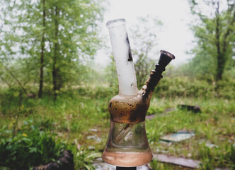 dirty glass bong on a background of gloomy nature