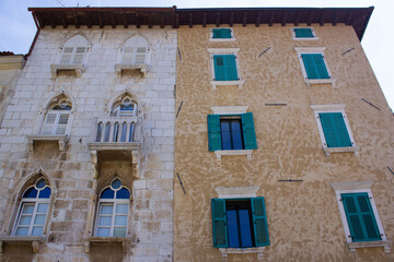 Naklejka premium Two different facades of old houses with green shutters in the old town of Porec (Parenzo), in the Istrian Peninsula, Croatia