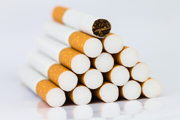 Closeup of many cigarettes The cigarette end is brown and the tip is white. Arranged in a triangle On a white background