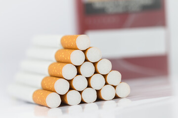 Closeup of many cigarettes The cigarette end is brown and the tip is white. Arranged in a triangle And there is a red cigarette case placed at the back On a white background On a white background