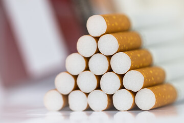 Closeup of many cigarettes The cigarette end is brown and the tip is white. Arranged in a triangle And there is a red cigarette case placed at the back On a white background On a white background