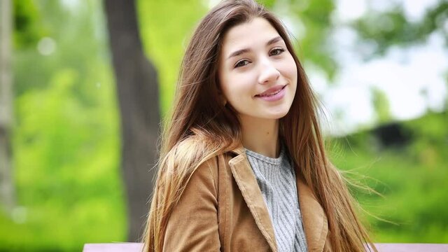 Portrait of happy cheerful young woman enjoying nature in the park. Beautiful   girl smiling at camera outdoors