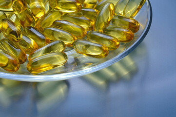 Fish oil capsules on a glass plate. A lot of vitamin omega 3. Close-up.