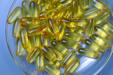 Fish oil capsules on a glass plate. A lot of vitamin omega 3. Close-up.