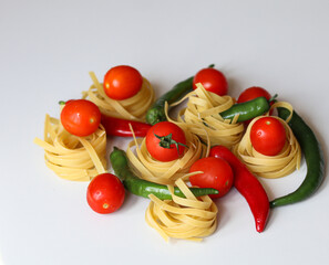 tomatoes, chili peppers and pasta on a white background