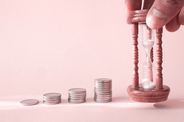 Piles of coins are laid out in increasing number of coins in a stack on a pink background and...