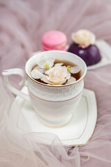 Composition on a light background: tea with flower petals, sweets and flowers. Still life with flowers and fruit tea