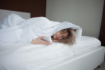 Morning, the woman under the blanket, turns off the alarm clock