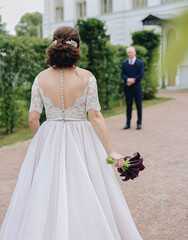 The bride goes to the groom with a bouquet of flowers