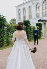 The bride goes to the groom with a bouquet of flowers