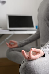 Teen girl is training at home, doing yoga exercises, sitting in lotus position, meditation. Body close-up, focus on the hand. Remote workout at home.