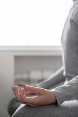 Teen girl is training at home, doing yoga exercises, sitting in lotus position, meditation. Body close-up, focus on the hand. Remote workout at home.