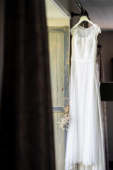 Wedding dress hanging from rail in front of a window