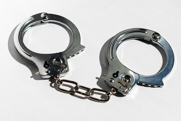 Steel handcuffs closeup on a white background.