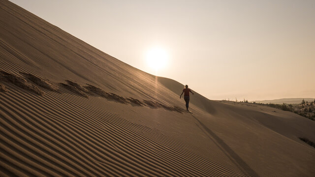 A Silhouette of Person is Walking on the Virgin Sand At Sunrise in White Sand Dunes During a Trip to Mui Ne, Phan Thiet, VIETNAM