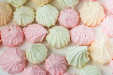 Colorful meringue sweets dessert on white background. Yellow mint green and pink