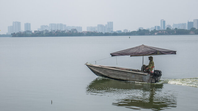 Hanoi City / Vietnam - May, 26, 2019: A Vietnamese Man is Fishing on the Boat With Umbrella in West Lake (Ho Tay)