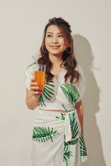 Happy Asian woman in summer casual clothes with a glass of fresh fruit juice drink