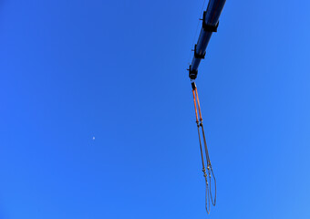 Crane hook on lifting gears and chains hanging of the mobile auto crane on a background blue sky