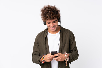 Young handsome man listening music with a mobile over isolated white wall