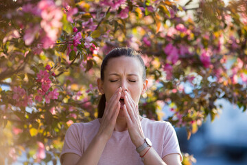 Woman sneezing because of spring pollen allergy