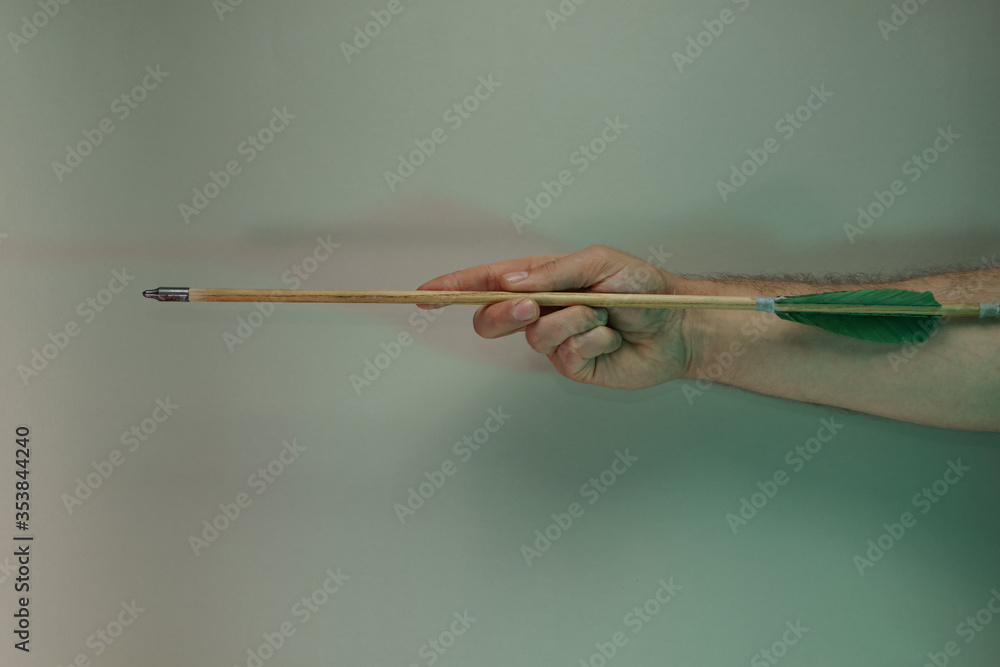 Poster Hand holding old green arrows in the color light. Beautiful old arrow minimal in neon light. Minimalism retro style concept. Background pattern for design.