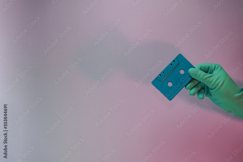 Poster Green Hand holding audio cassette tape in the color light. Beautiful minimal in neon light. Minimalism retro style concept. Background pattern for design.