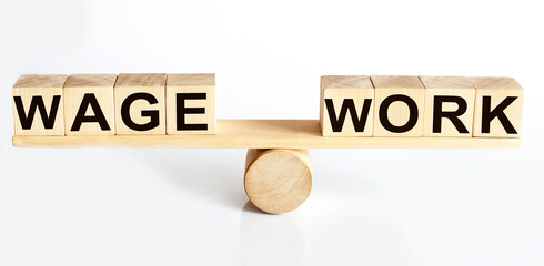 Wooden seesaw representing imbalance between WAGE and WORK isolated over white background