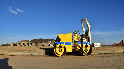 Obraz premium Paving roller machine during road work. Mini road roller at construction site for paving works. Screeding the sand for road concreting. Asphalt pavement is layered over concrete pavement