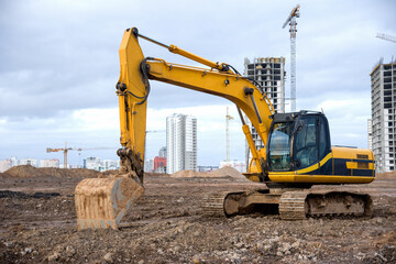 Excavator during earthmoving at construction site. Backhoe dig ground for the construction of foundation and laying sewer pipes district heating. Earth-moving heavy equipment on road works