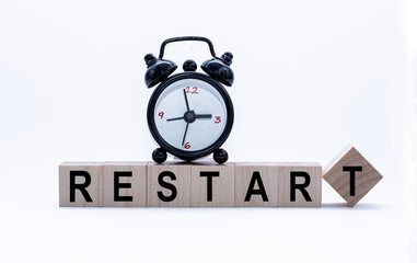 Business concept: Restart Word on Wooden Blocks and alarm-clock. Time is money. Time-limit.
